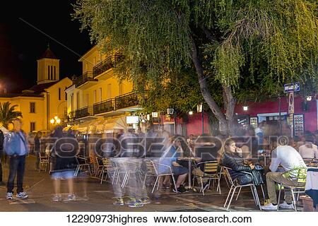 Stock Photograph - Tourists sit at cafe tables at nighttime; San Teodoro, Sardinia, Italy. Fotosearch