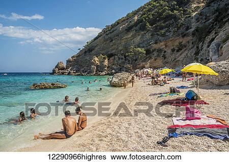 Stock Photograph - Tourists swimming and sunbathing along the Mediterranean coast; Cala Gonone, Sardinia, Italy. Fotosearch