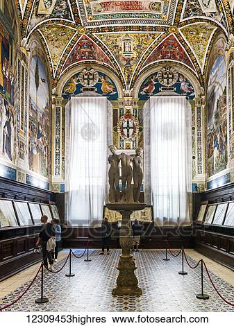 Stock Photograph - Tourists view exhibits on a wall in a room with colourful, ornate facade; Siena, Italy. Fotosearch