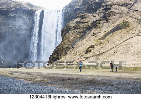 Stock Photograph - Tourists visit the Seljalandsfoss waterfall; Iceland. Fotosearch