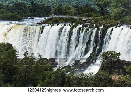 Stock Photograph - Tourists watching Iguazu Falls from observation deck; Parana, Brazil. Fotosearch