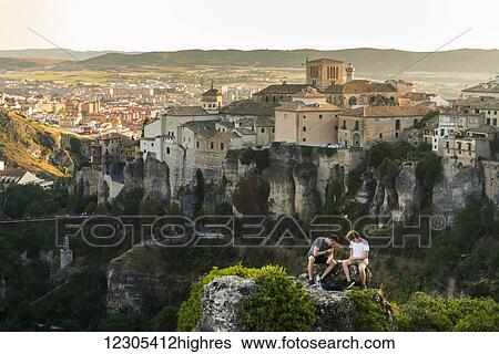 Stock Photograph - Two friends having rest in the surroundings of Cuenca with a beautiful landscape behind them; Cuenca, Castile-La Mancha, Spain. Fotosearch