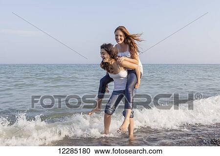 Two girls playing piggyback at beach; Toronto, Ontario, Canada View Large Photo Image Stock Image - Two girls playing piggyback at beach; Toronto, Ontario, Canada. Fotosearch