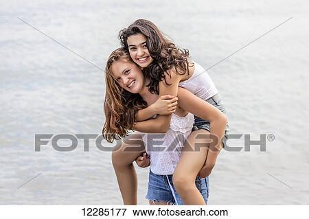 Two girls playing piggyback at beach; Toronto, Ontario, Canada View Large Photo Image Stock Photo - Two girls playing piggyback at beach; Toronto, Ontario, Canada. Fotosearch