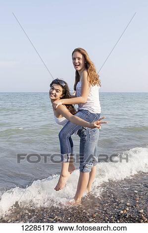 Two girls playing piggyback at beach; Toronto, Ontario, Canada View Large Photo Image Stock Photo - Two girls playing piggyback at beach; Toronto, Ontario, Canada. Fotosearch
