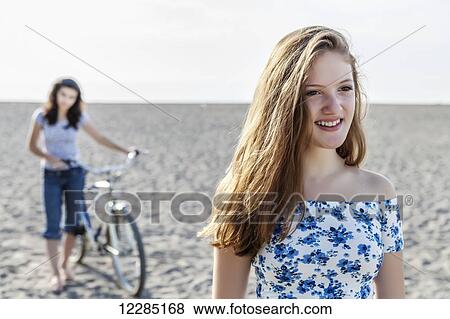 Two girls standing on a beach with bike; Toronto, Ontario, Canada View Large Photo Image Stock Photo - Two girls standing on a beach with bike; Toronto, Ontario, Canada. Fotosearch