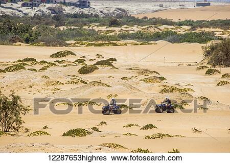 Stock Photograph - Two people riding a four wheeler through the desert; Swakopmund, Namibia. Fotosearch