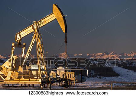 Two pump jacks at sunrise reflecting the warm morning light in a snow covered field and snow covered foothills and mountains in the background lit by the morning sun; Alberta, Canada View Large Photo Image Stock Photograph - Two pump jacks at sunrise reflecting the warm morning light in a snow covered field and snow covered foothills and mountains in the background lit by the morning sun; Alberta, Canada. Fotosearch