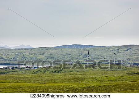 Stock Photograph - Two wind turbines sit above the city of Sand Point, Sand Point, Popof Island, Southwestern Alaska, USA, Summer. Fotosearch