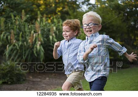 Two young boys with big smiles running together on grass; Raleigh, North Carolina, United States of America View Large Photo Image Stock Photography - Two young boys with big smiles running together on grass; Raleigh, North Carolina, United States of America. Fotosearch