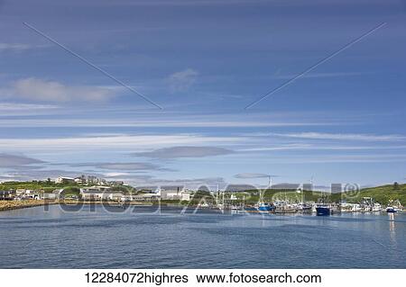 Stock Photograph - View of Sand Point harbor and breakwaters of Popof Island on a sunny day, Southwestern Alaska, USA, summer. Fotosearch