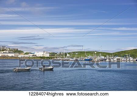 Stock Photograph - View of Sand Point harbor with two skiffs in the foreground, Popof Island, Southwestern Alaska, USA, summer. Fotosearch