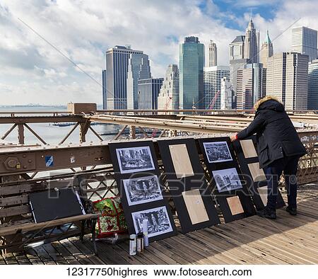 Stock Photograph - View of the New York City skyline from the Brooklyn Bridge with an artist vendor in the foreground; New York City, New York, United States of America. Fotosearch