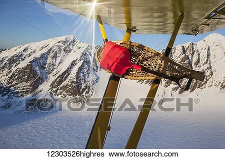 Stock Photograph - View of traditional snowshoes tied to wing struts of a Piper PA-18 Super Cub while in flight around the Kenai Mountains, Alaska. Fotosearch