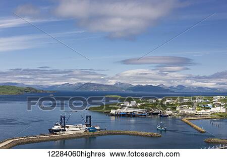 Stock Photograph - View Sand Point harbor and breakwaters of Popof Island on a sunny day, Southwestern Alaska, USA, summer. Fotosearch