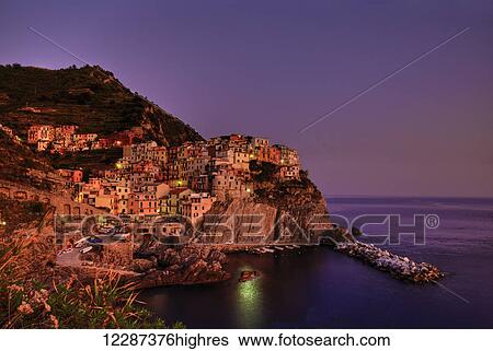 Stock Photograph - Village on the coast at sunset; Manarola, Riomaggiore, Italy. Fotosearch