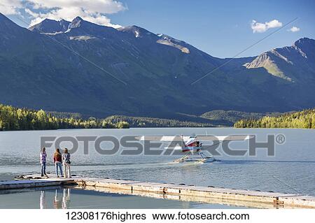 Stock Photograph - Visitors watch a float plane depart, Trail Lake Float Plane Base, Moose Pass, Kenai Peninsula, Southcentral Alaska, USA. Fotosearch