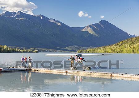 Stock Photograph - Visitors wave to the pilot standing on a Super Cub float plane, Trail Lake Float Plane Base, Moose Pass, Kenai Peninsula, Southcentral Alaska, USA. Fotosearch