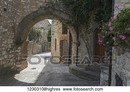 Stock Photograph - Walkway past stone walls and an archway by residential buildings; Gaiole in Chianti, Toscana, Italy. Fotosearch