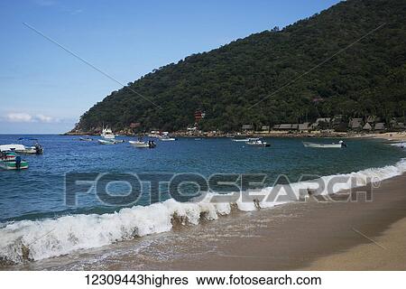Stock Photograph - Waves breaking along the beach with boats in the water just off the shore; Yalepa, Jalisco, Mexico. Fotosearch