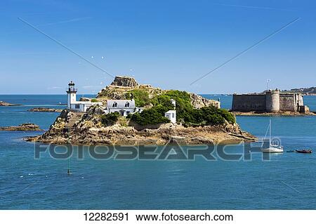 Stock Image - White lighthouse on an island with stone castle and turret also on an island in the background with blue water and sky; Carantec, Brittany, France. Fotosearch