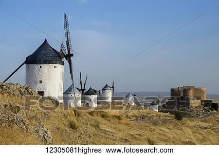 Stock Photograph - Windmills in a row along a grass hillside; Consuegra, Spain. Fotosearch