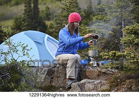 Stock Photograph - Woman backpacker prepares a meal at camp near Upper Fuller Lake in the Kenai National Wildlife Refuge on the Kenai Peninsula in South-central Alaska. Fotosearch