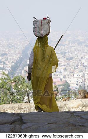 Stock Photograph - Woman carrying bag on head; Dharpatha Mal, Madhya Pradesh, India. Fotosearch