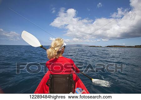 Stock Photograph - Woman kayaking in South Maui with West Maui Mountains in the background; Makena, Hawaii, United States of America. Fotosearch