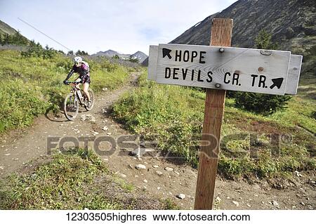 Stock Photograph - Woman rides a full suspension mountain bike on the Devils Pass Trail in the Chugach National Forest, Kenai Peninsula, Southcentral Alaska. Fotosearch