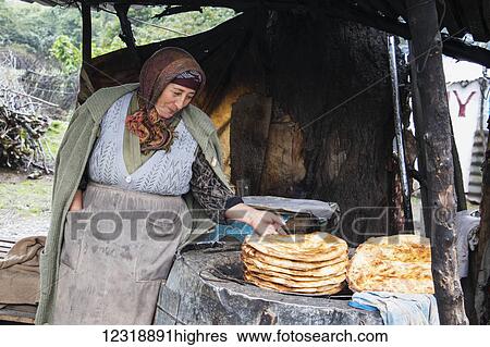 Stock Photograph - Woman selling salyan coreyi (tandoor bread) by the road side; Sheki, Azerbaijan. Fotosearch