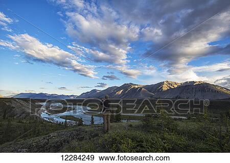Woman taking pictures while looking out at the Wind River in the Peel Watershed; Yukon, Canada View Large Photo Image Stock Photo - Woman taking pictures while looking out at the Wind River in the Peel Watershed; Yukon, Canada. Fotosearch