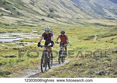 Stock Photograph - Women ride full suspension mountain bikes on the Resurrection Pass Trail in the Chugach National Forest, Kenai Peninsula, Southcentral Alaska. Fotosearch