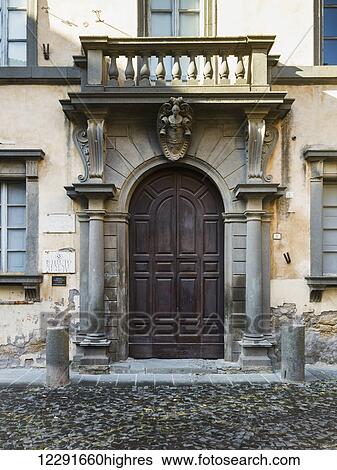 Stock Photograph - Wooden arched door and pillars with a small balcony on a residential building; Orvieto, Umbria, Italy. Fotosearch