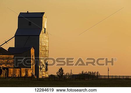 Wooden grain elevator refecting the orange glow of sunrise; Mossleigh, Alberta, Canada View Large Photo Image Stock Photo - Wooden grain elevator refecting the orange glow of sunrise; Mossleigh, Alberta, Canada. Fotosearch