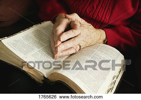 Stock Photograph - Senior praying with Bible. Fotosearch