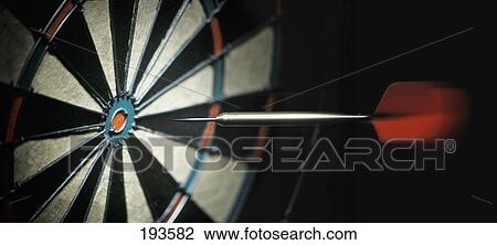 Stock Image - Dart flying to dartboard. Fotosearch