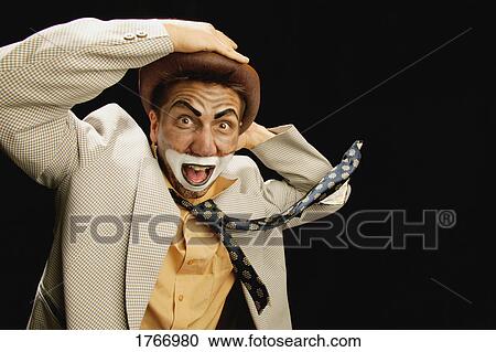 Stock Image - A clown holds onto his hat. Fotosearch