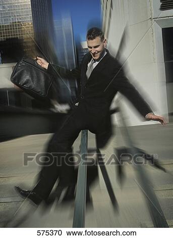 Stock Image - Man slides down handrail in celebration. Fotosearch