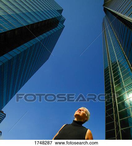Stock Photo - Woman stands by office towers. Fotosearch
