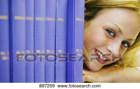 Female student peeking around books View Large Photo Image Stock Photo - Female student peeking around books. Fotosearch
