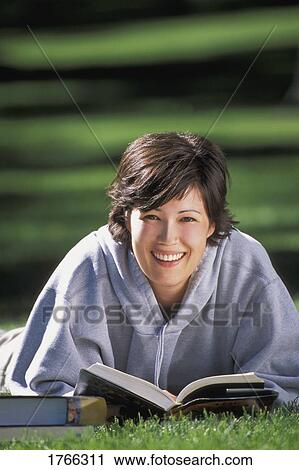 Stock Image - Woman with book on the grass. Fotosearch