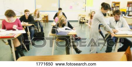 Stock Image - Teacher helping student in classroom. Fotosearch
