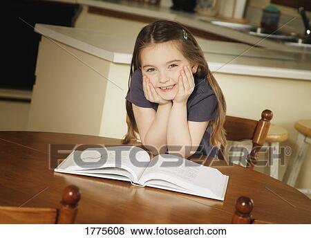 Young girl sat at the kitchen table reading View Large Photo Image Stock Photo - Young girl sat at the kitchen table reading. Fotosearch