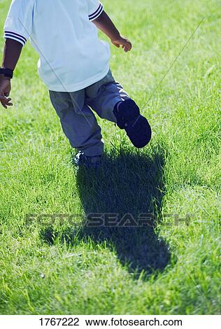 Stock Image - Child runs through grass. Fotosearch
