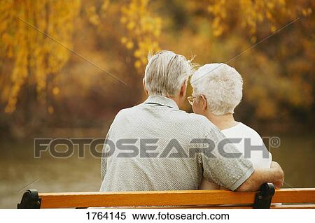 Couple sit together on a bench View Large Photo Image Stock Photography - Couple sit together on a bench. Fotosearch