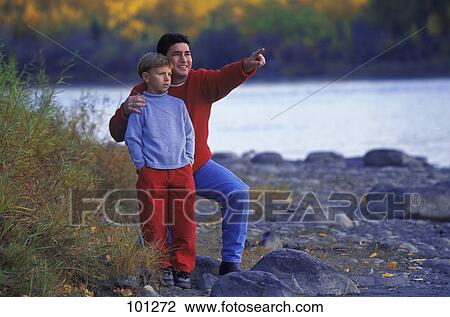 Stock Image - Father and son on rocky river shore. Fotosearch