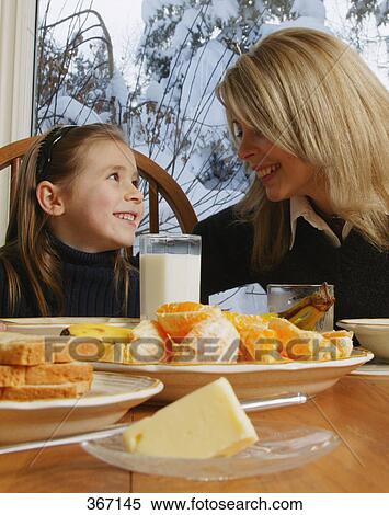 Stock Photography - Mother daughter smile at breakfast table. Fotosearch