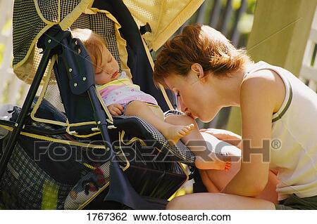 Stock Image - Mother kisses sleeping daughter. Fotosearch