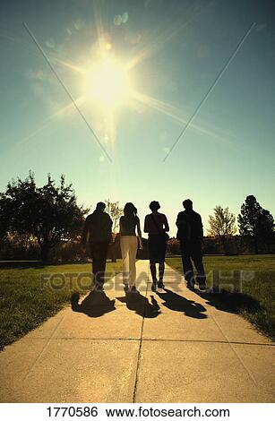 Four people walking down a path View Large Photo Image Stock Photograph - Four people walking down a path. Fotosearch